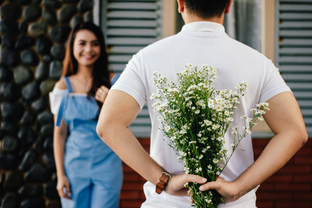 a man holding flower in front of woman