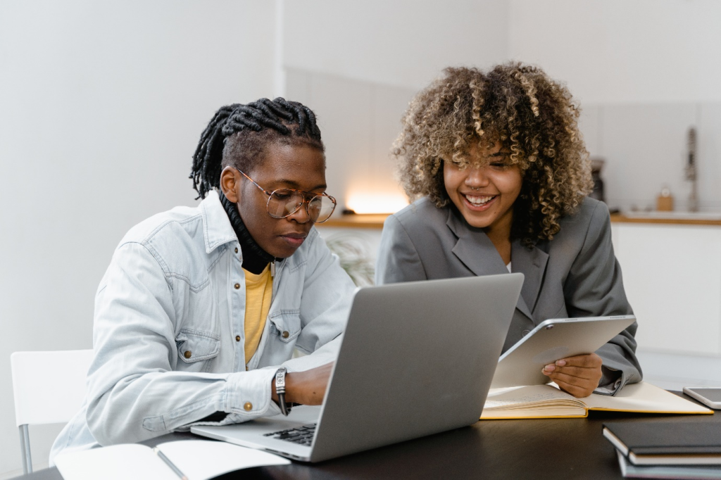 man and woman having a conversation while sitting near the table with a laptop