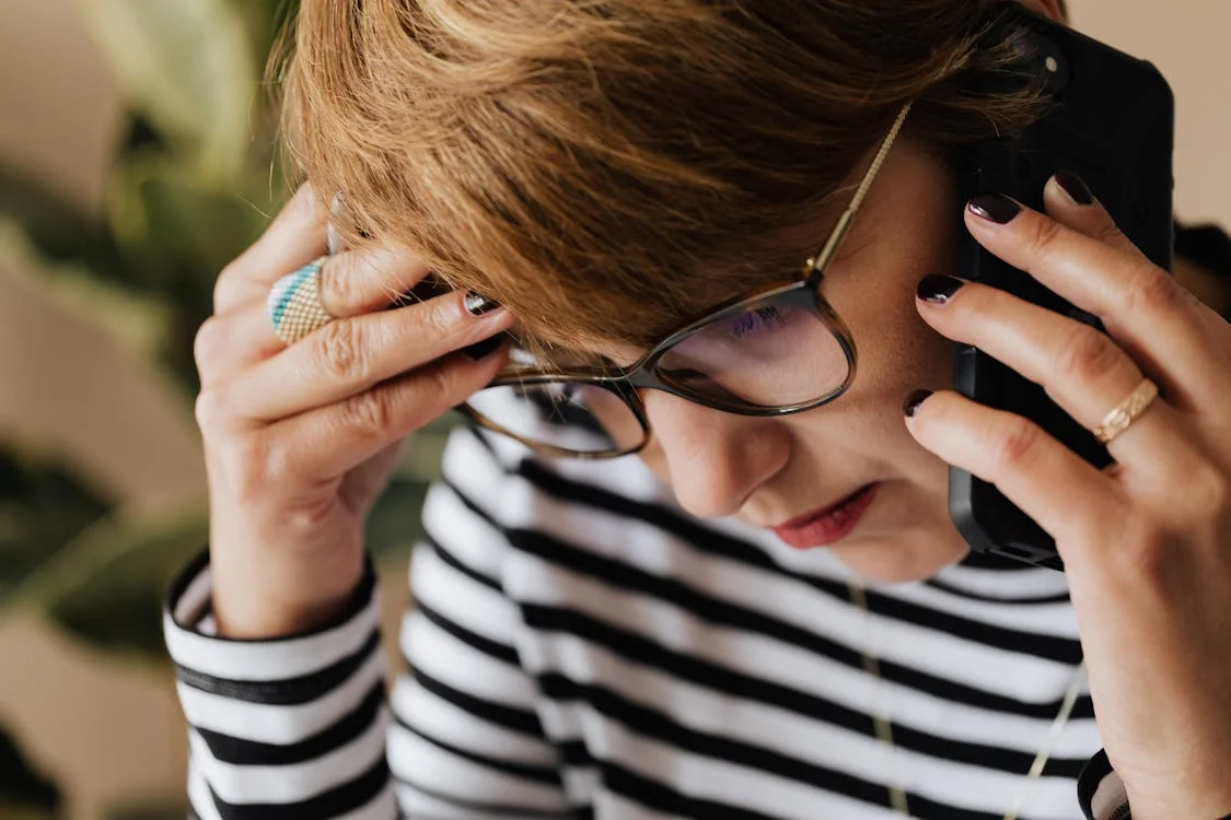 A person sitting at a table, anxiously checking their phone while looking away