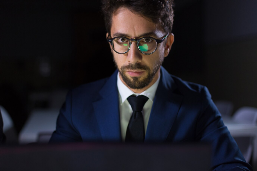 an investigator sitting at table with laptop and looking at camera