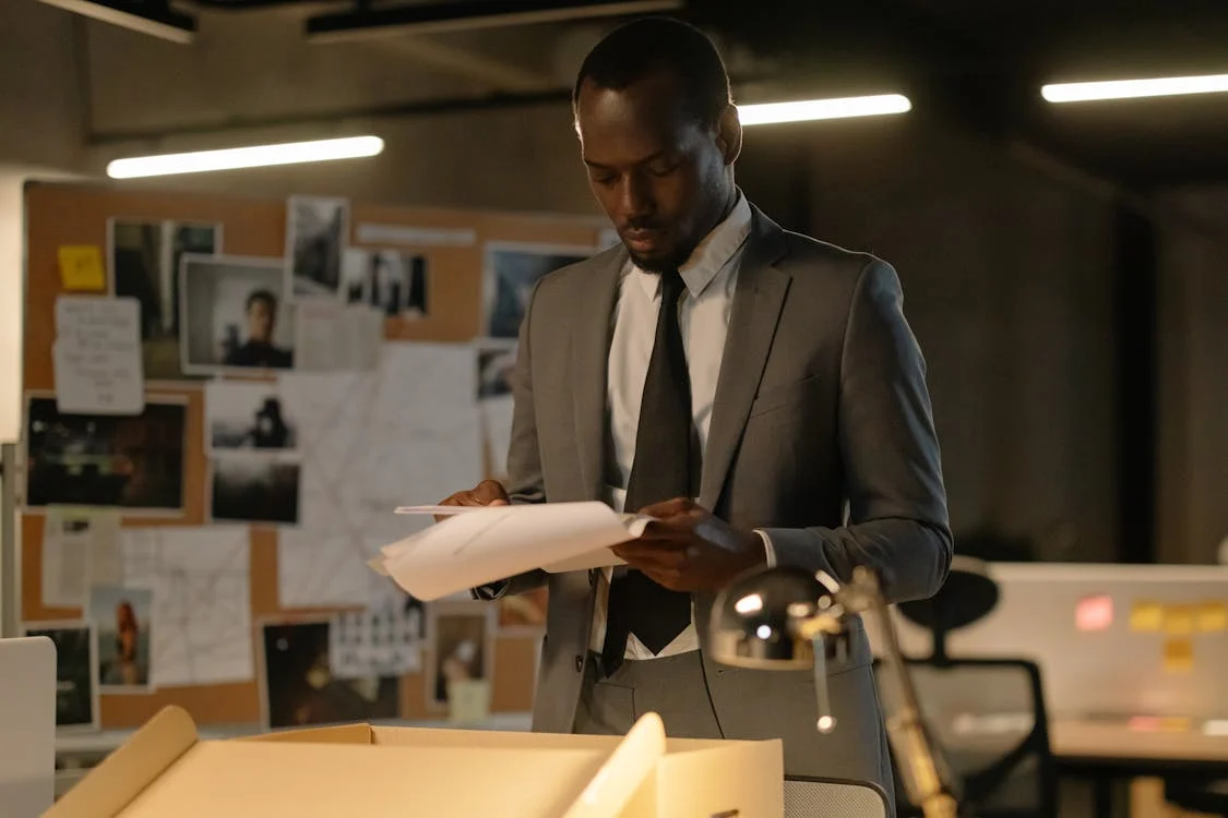 A private investigator reviewing case files on a desk.